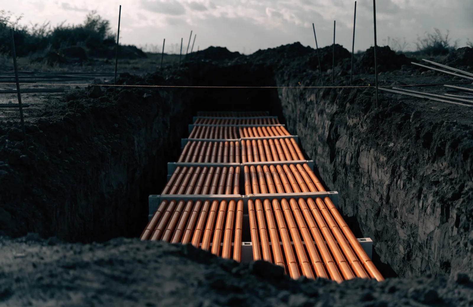 Bank of electrical conduits on spacers in a shared utility trench before concrete encasement