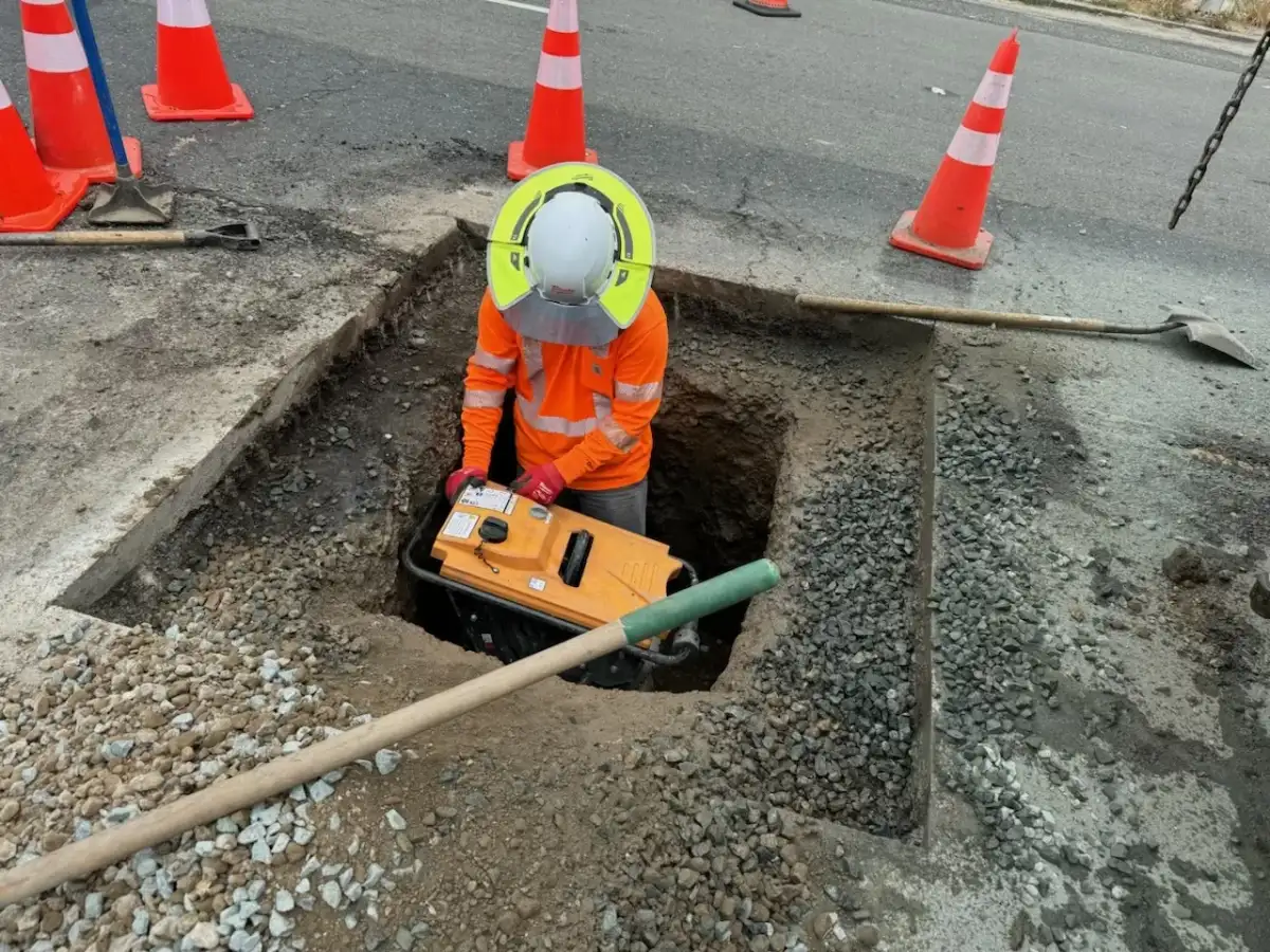 Open-cut trench with compaction equipment during an underground utility installation