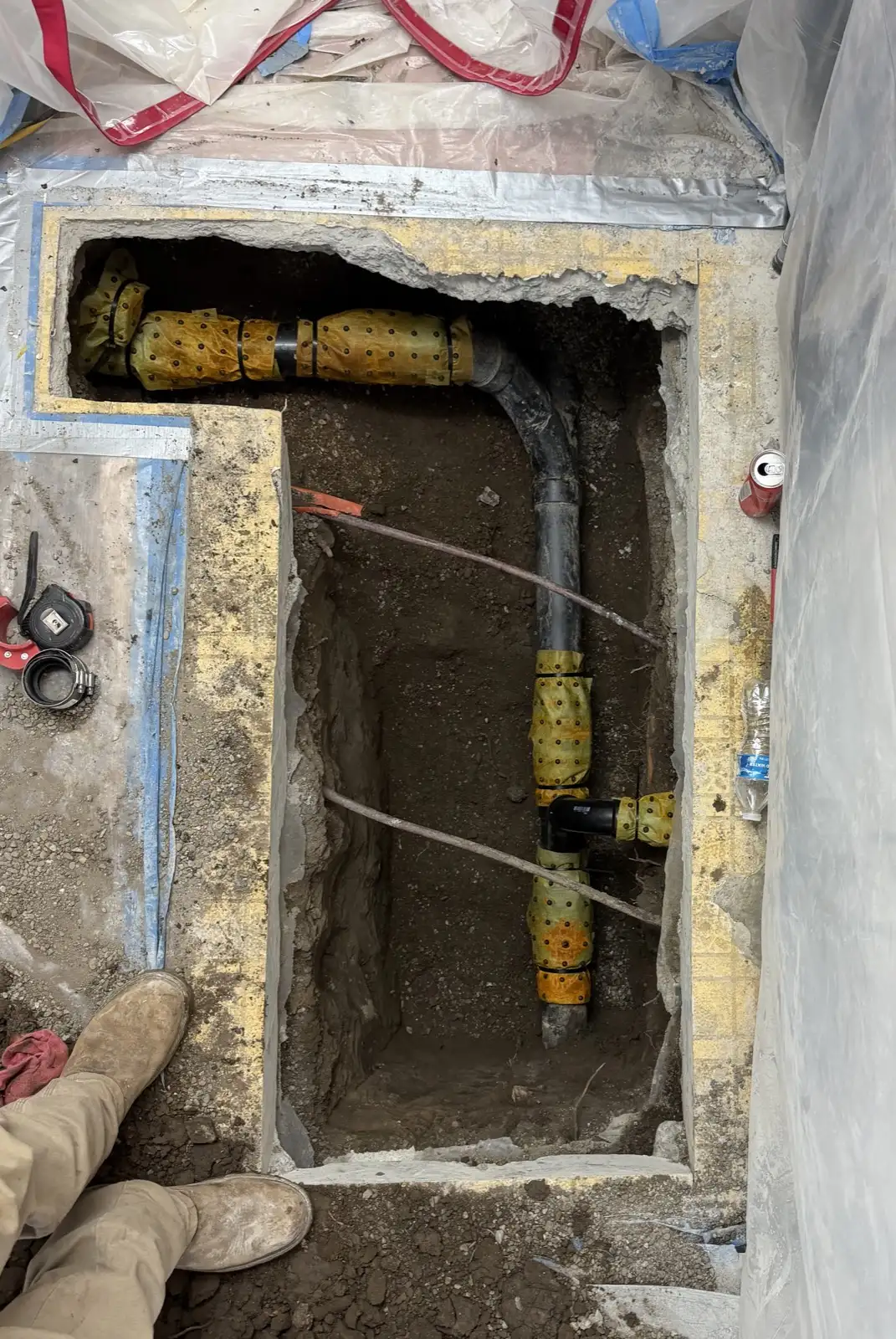 New under-slab drain line wrapped for protection before the trench is backfilled