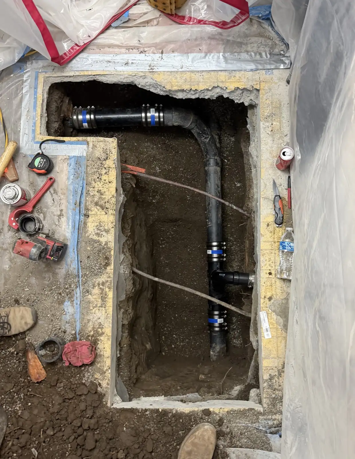 New drain line with no-hub couplings installed in the excavation beneath the kitchen slab