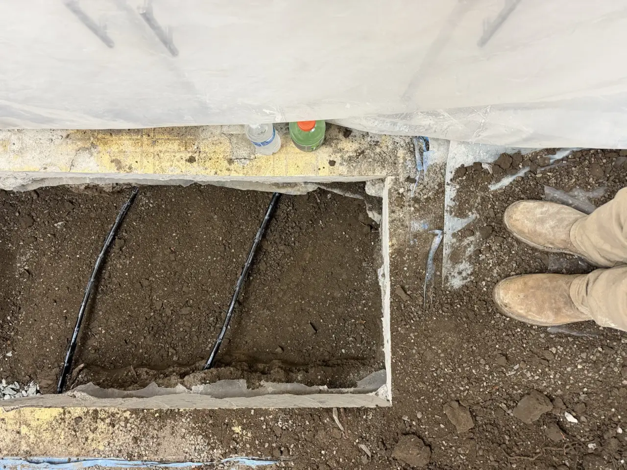 Under-slab trench with the new drain line bedded in ahead of backfill