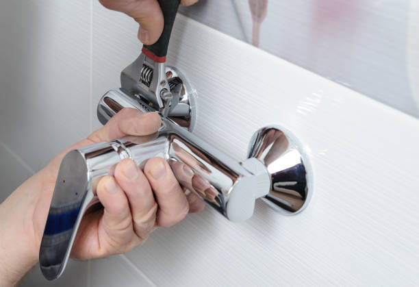 Man's hands fixing a shower faucet with a adjustable wrench.